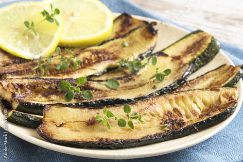 roasted zucchini slices with lemon and herb garnish on a plate, delicious mediterranian vegetables for healthy eating
