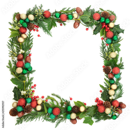 Festive Christmas and winter square wreath with fir leaf sprigs, holly berries, ivy, mistletoe, bauble decorations, laurel, pine cones and acorns on white background with copy space.