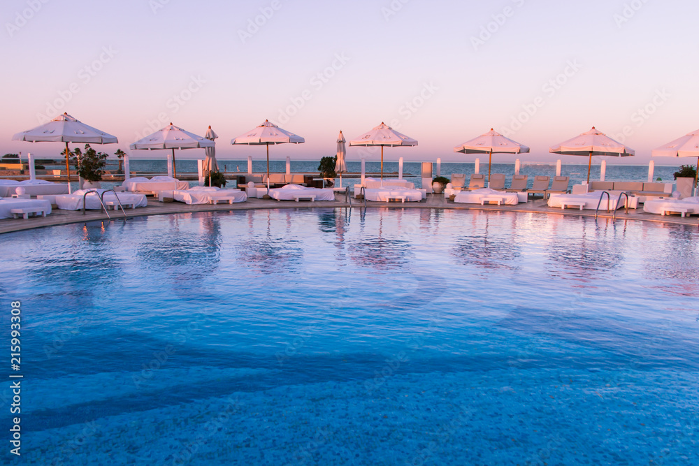 Pastel Sunset Light over Swimming Pool and Sun Beds.