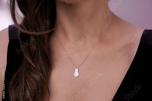 Girl wearing a gold necklace with a snowman pendant