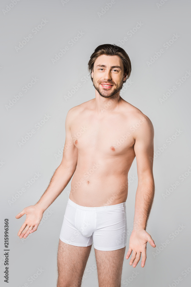 portrait of young man in white underwear looking at camera isolated on grey