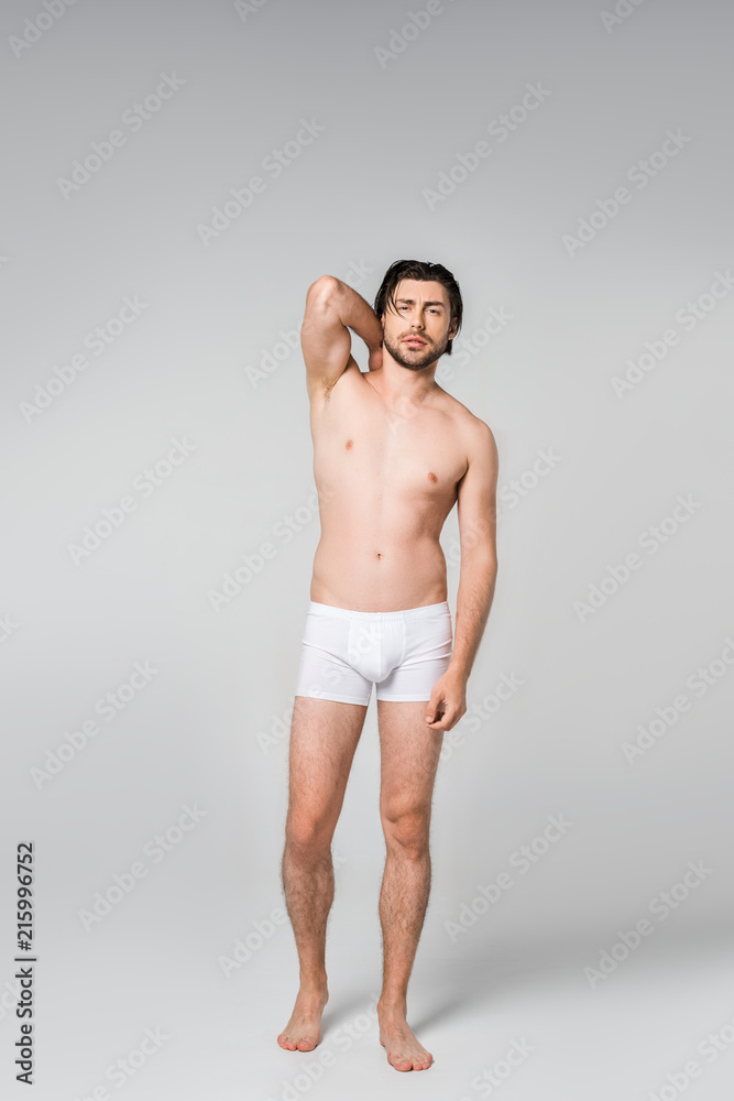 thoughtful man in white underwear posing on grey backdrop