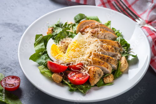 Caesar salad with chicken breast and tomatoes.