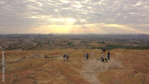 American Tourists Watch as Sunbeams Peak Through Clouds by a Mountain in Rural Africa at Sunset photo