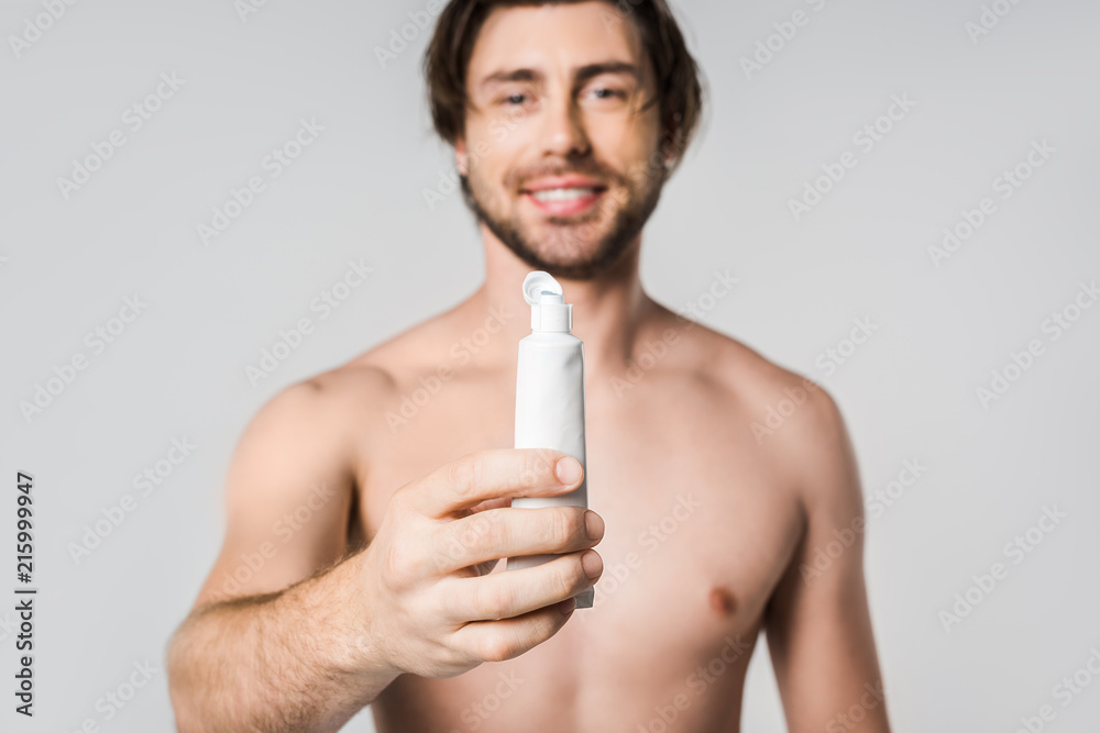 Fototapeta premium selective focus of cheerful shirtless man showing toothpaste isolated on grey