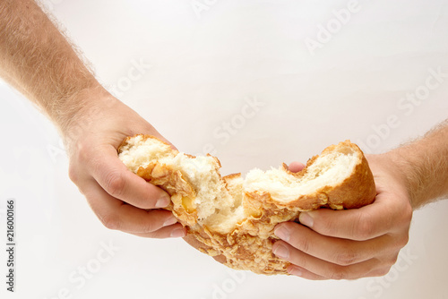 Bread is torn in half in male hands on the white background