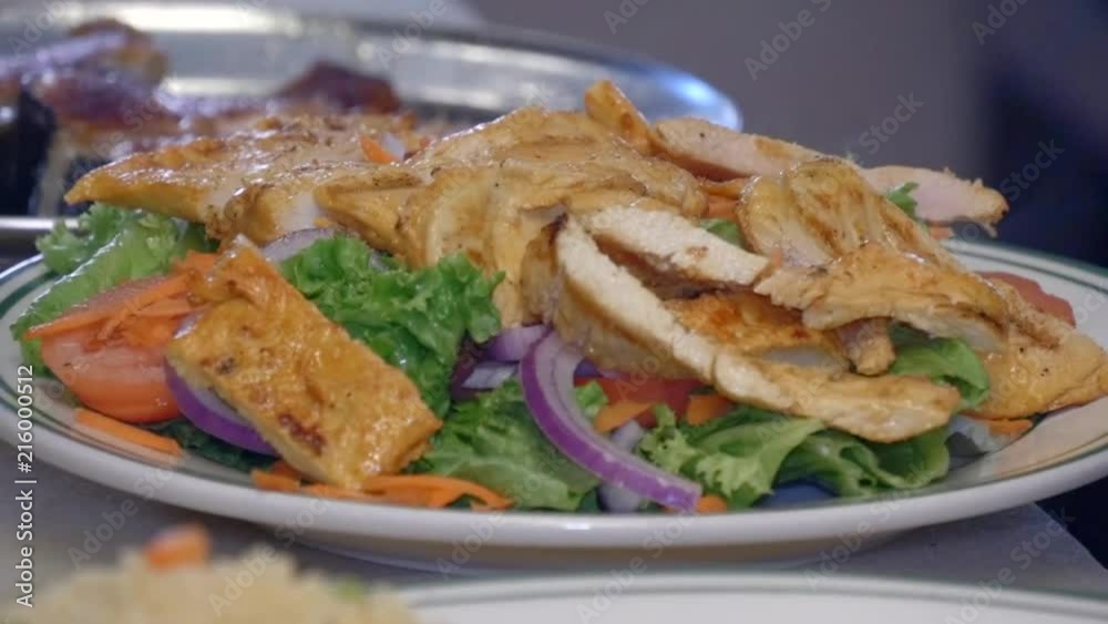 Plating fresh grilled chicken on salad greens. Plating fresh grilled chicken on salad greens.