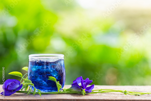 Fresh purple Butterfly pea or blue pea flower and juice in glass on wooden table background photo