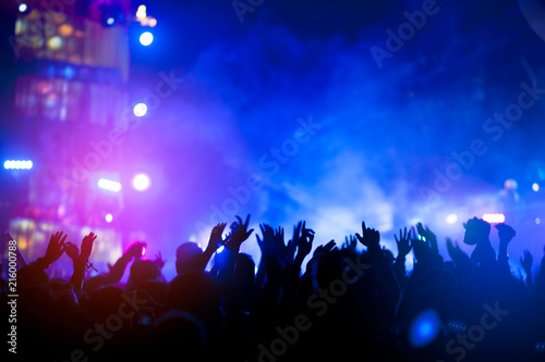 silhouettes of hand in concert.Light from the stage.confetti.the crowd of people silhouettes with their hands up.ribbon
