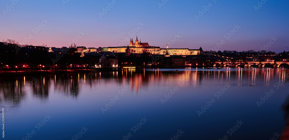 Beleuchtetes Schloss hinter der Moldau am späten Abend in Prag, Tschechien