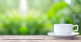 Coffee cup on wooden table or counter with green nature light blur background