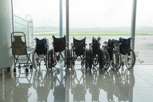 Wheelchair by the glass window in the airport background of runway taxi way and mountain.