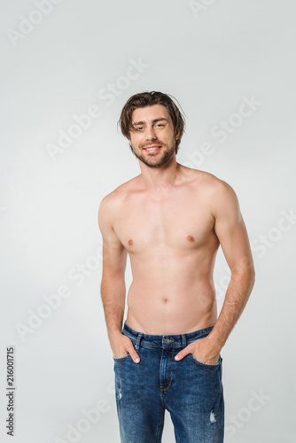 portrait of happy shirtless man in jeans isolated on grey