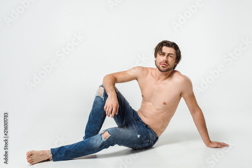 young shirtless man in jeans posing on grey backdrop