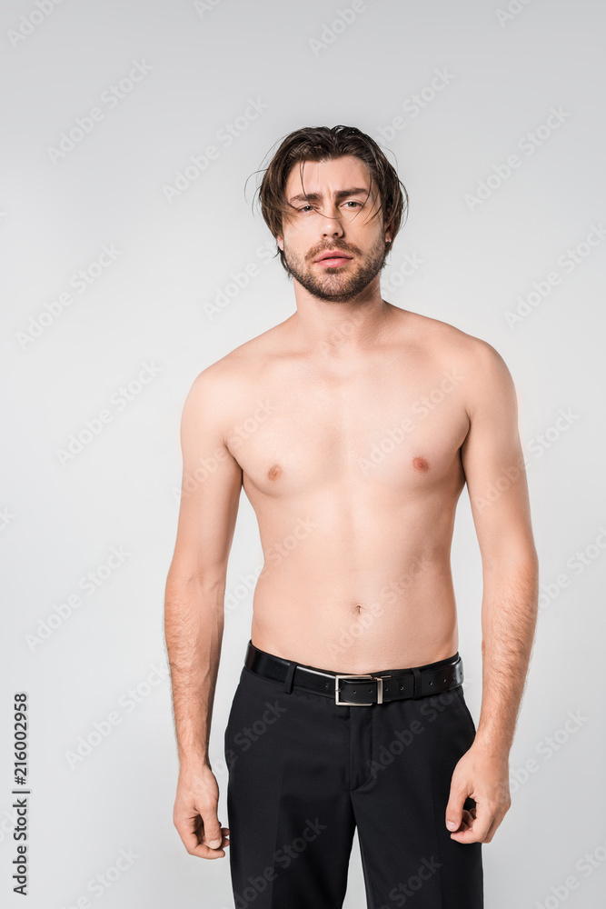 portrait of shirtless pensive man in black pants on grey background