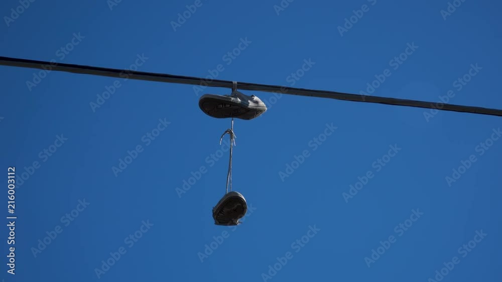 Converse chucks hanging on electricity wire in suburban street to signal nearby local drug trade. Converse chucks hanging on electricity wire in suburban street to signal nearby local drug trade.