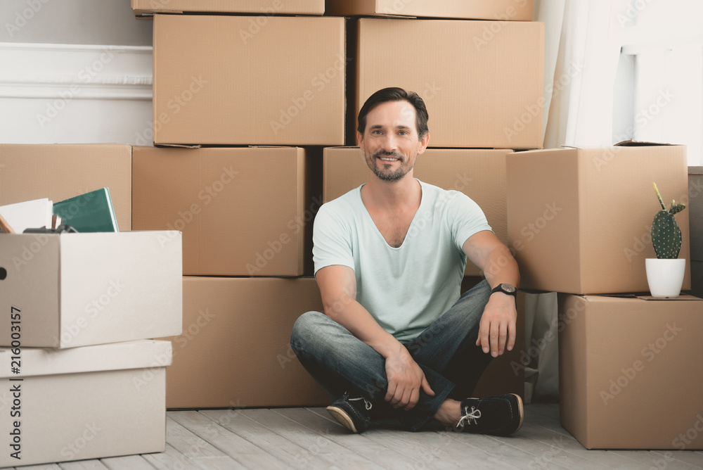 Bearded Caucasian Sits near Large Cardboard Boxes. Bearded Caucasian Sits near Large Cardboard Boxes.
