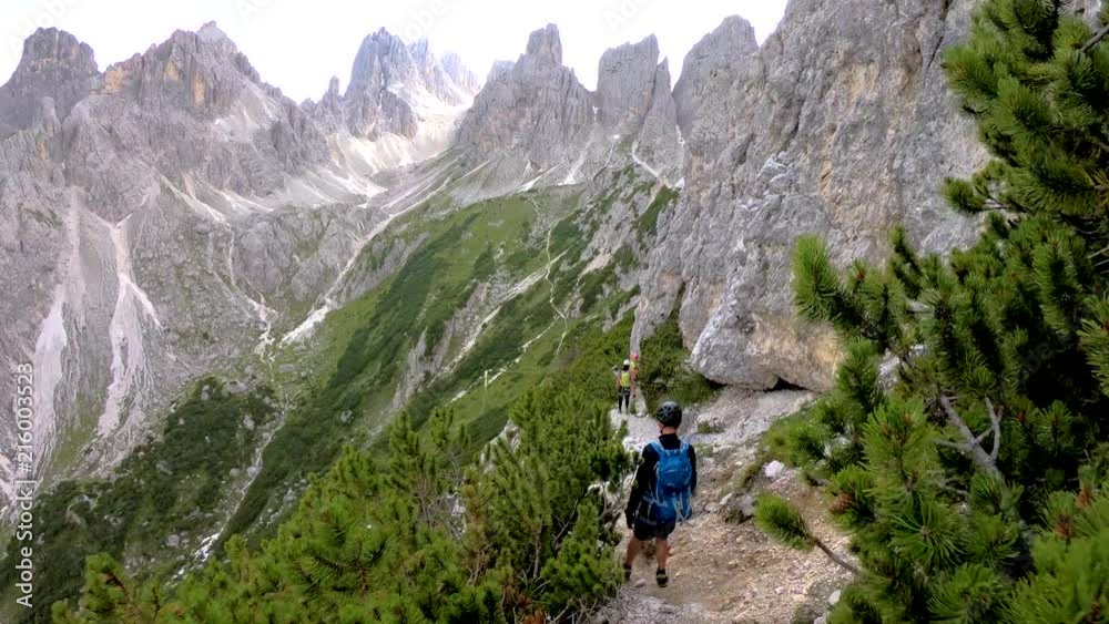 Man walking on the edge of a cliff high above the mountains. Via ferrata Italian Dolomites. Trail walking in Dolomites. On the ridge. Man hiking with the backpack on the edge of the mountain. Tourists Man walking on the edge of a cliff high above the mountains. Via ferrata Italian Dolomites. Trail walking in Dolomites. On the ridge. Man hiking with the backpack on the edge of the mountain. Tourists