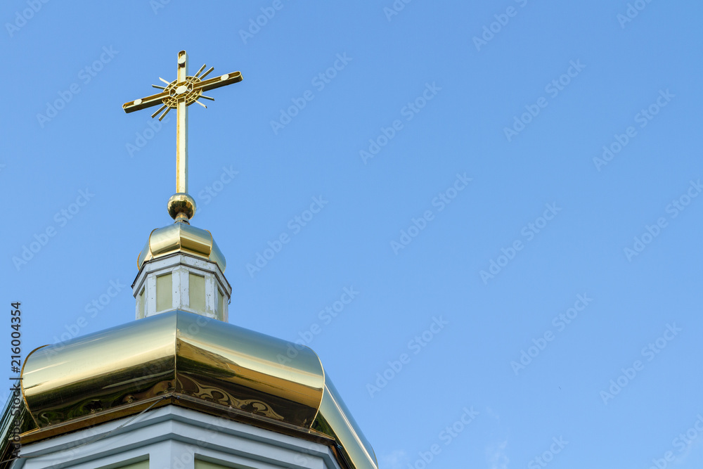 Cross on the golden dome of the Orthodox church against the blue sky. The cross is a symbol of Orthodoxy. The Golden Cross is a symbol of the Church of Jesus Christ.