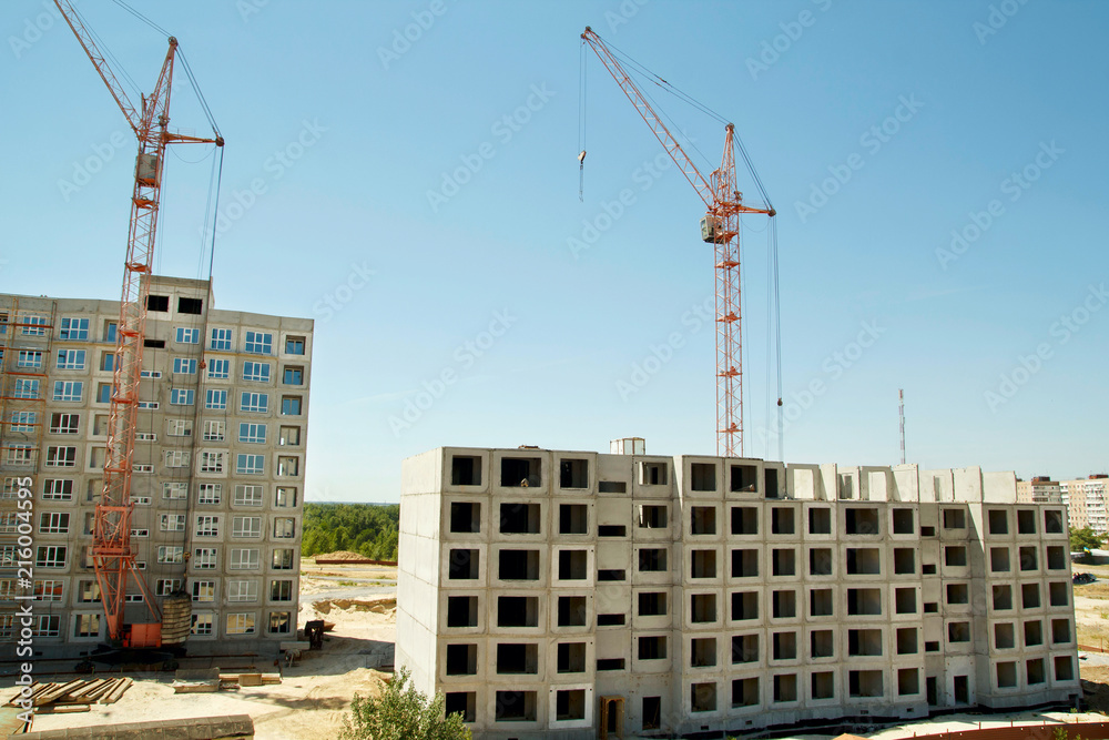 Picture of construction cranes building two big houses