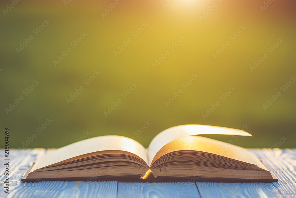 Book on wooden table with abstract blur and bokeh in sunrise or sunset time