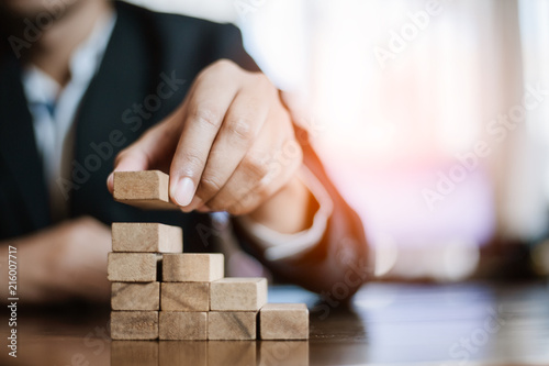 plan and strategy in business.risk concept.hand of man has piling up and stacking a wooden block.Businessman Building The Success.