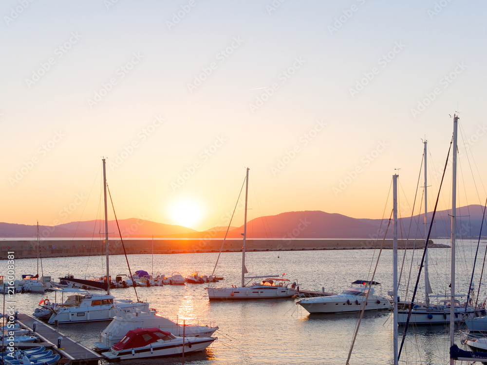 View of the beautiful harbor and boats in Alghero at sunset. Sardinia, Italy.