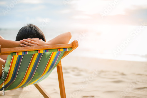 Woman relaxing on beach, looking at sea. Copy space.