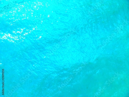 Aerial view on blue ocean water with sun reflections