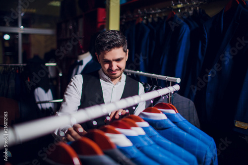 Tailor, tailoring. Men's suit, tailor in his workshop. Elegant man's suits hanging in row. Luxury mens classic suits on rack in elegant men's boutique. photo