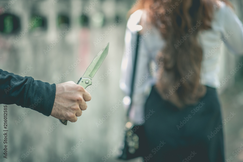 A bandit holds a knife. In order to attack and steal a woman's belongings from the back.