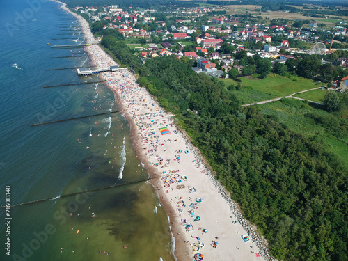 Aerial view on a sea with breakwaters, beach, trees and small city