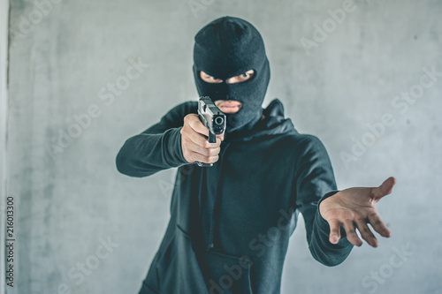 Fototapeta Naklejka Na Ścianę i Meble -  Robber with a gun robbing intimidate.Crime and robbery concept.