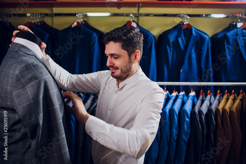 Tailor, tailoring. Men's suit, tailor in his workshop. Elegant man's suits hanging in row. Luxury mens classic suits on rack in elegant men's boutique. photo