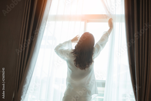 Free Download Asian woman wake up in the morning, sitting on white bed and stretching, feeling happy and fresh - GFXLoad