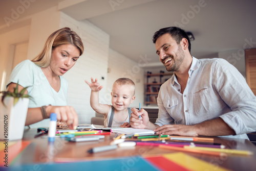 Mom, dad and son draw in the living room.