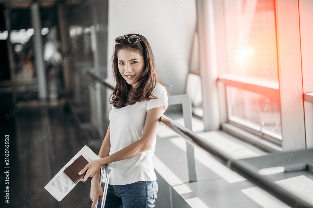 The woman was smiling and holding a travel document and passport in the airport terminal. The woman was smiling and holding a travel document and passport in the airport terminal.