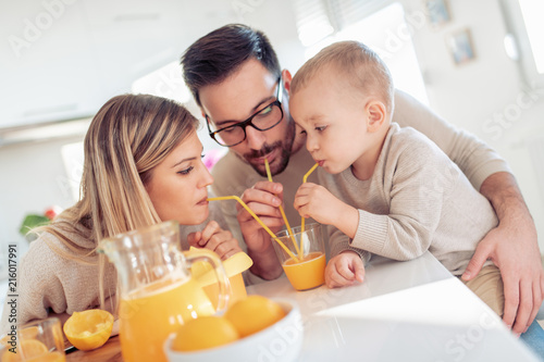 Cheerful young family making orange juice