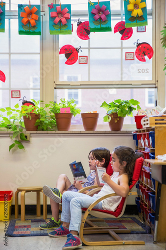Two classmates reading a book in s kindergarten classroom. 