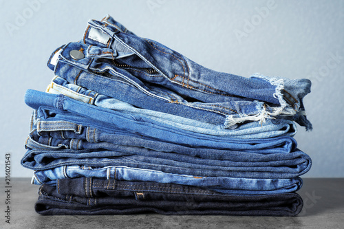 Stack of jeans on table against grey background