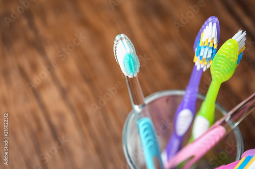 Cup with toothbrushes on wooden table  closeup. Dental care