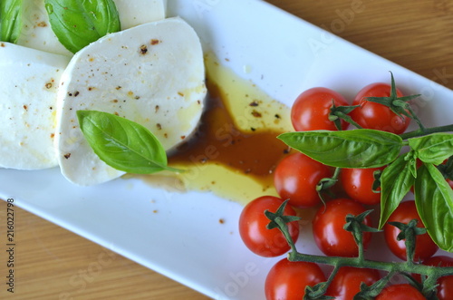 Italian Caprese salad. Close up of mozzarella cheese and cherry tomato salad with Balsamico vinegar, olive oil and basil top view