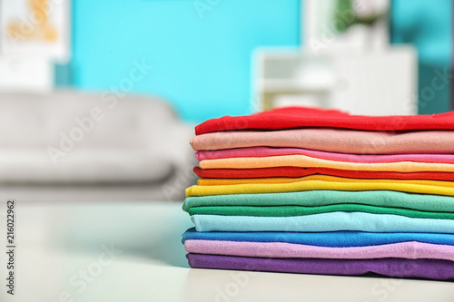 Stack of colorful t-shirts on table in living room