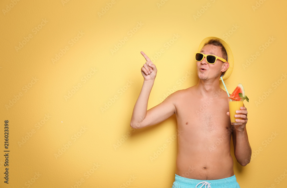Shirtless man with glass of cocktail on color background