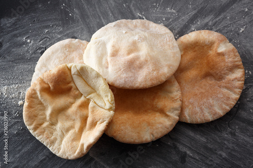 Pita bread on a black table sprinkled with flour