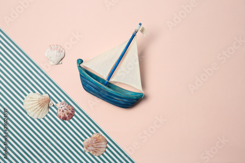 Flat lay composition with small boat and seashells on color background. Beach objects