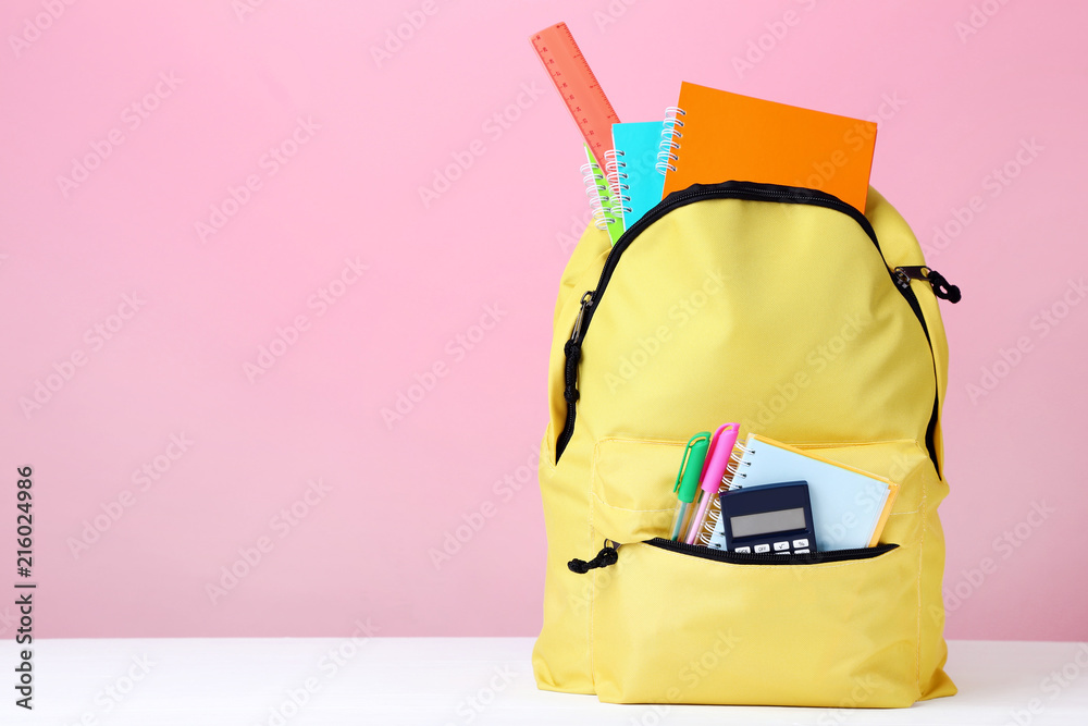Yellow backpack with school supplies on pink background - obrazy, fototapety, plakaty 