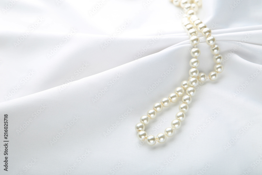 Pearl necklace on white satin fabric