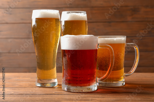 Glasses with different types of cold tasty beer on wooden table