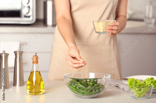 Woman preparing healthy salad with green beans at table